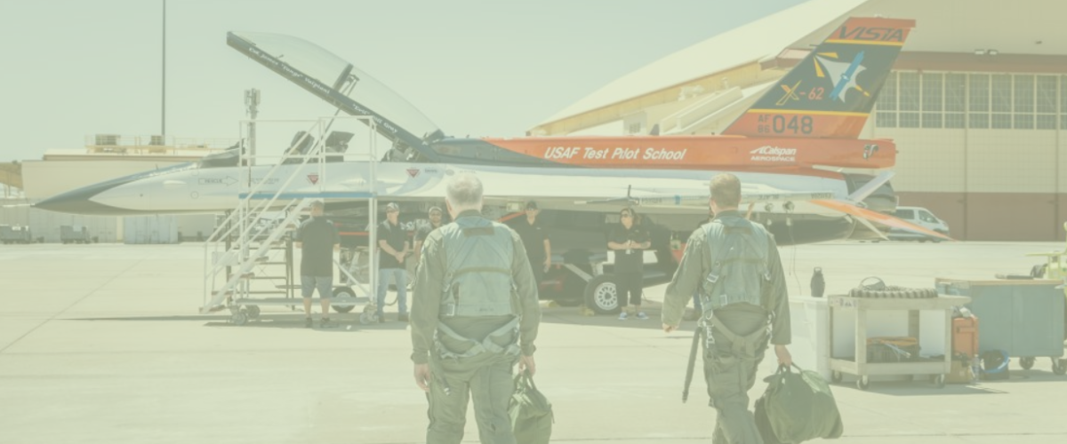  Two military personnel in uniform approach an AI-powered F-16 on the runway.